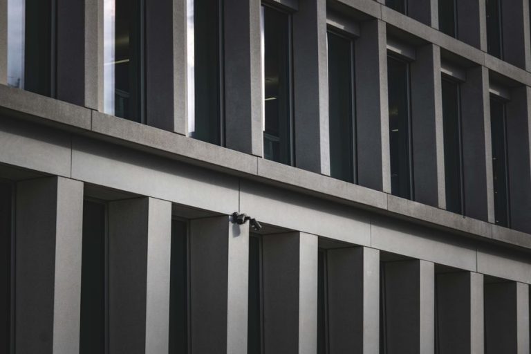 Contemporary office building exterior featuring multiple windows and security cameras.
