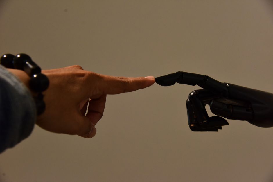 A human hand and a robotic hand extending fingers to touch, symbolizing connection.