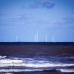 Ocean Energy: The Future of Industrial-Scale Power Autonomy Offshore wind turbines generating sustainable energy over a calm ocean under a clear blue sky.