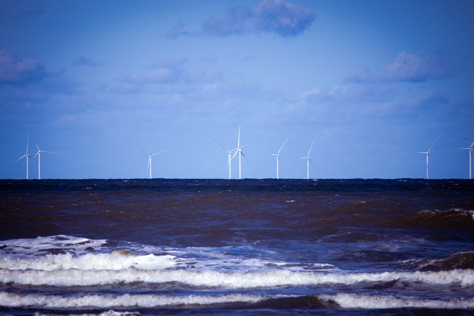 Offshore wind turbines generating sustainable energy over a calm ocean under a clear blue sky.