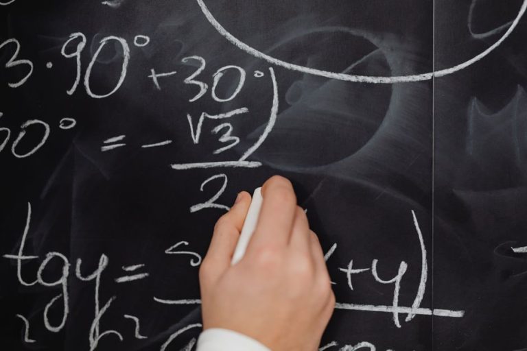 A hand vividly writing complex mathematical equations on a chalkboard.