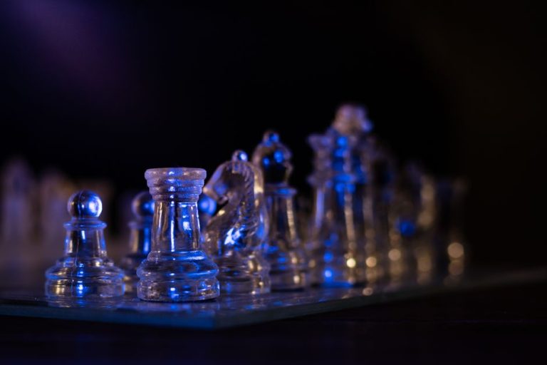 Transparent glass chess pieces with blue lighting create a striking and modern still life image.