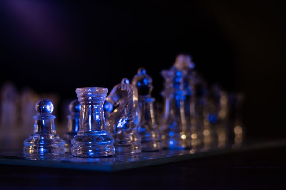 Transparent glass chess pieces with blue lighting create a striking and modern still life image.