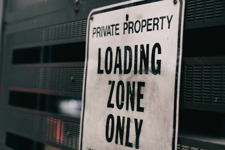 Close-up of a private property loading zone only sign with urban backdrop.