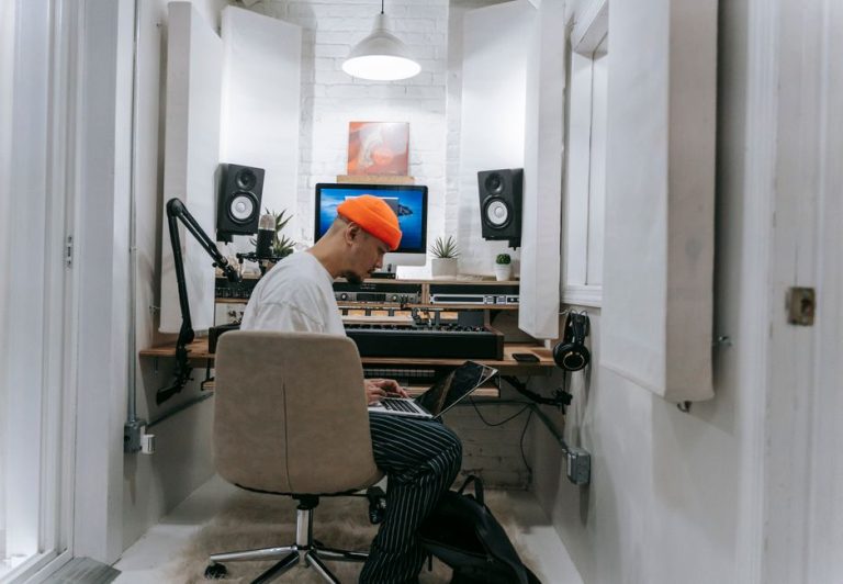 An adult male focuses on music production in a sleek, white recording studio setting.