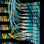 Closeup of switch in server with connectors and adapters connected to plastic device in dark room on blurred background inside