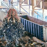 Orbital Debris: Managing Infrastructure Risks in Space Economy An industrial claw crane lifts metal scrap in a recycling facility, showcasing efficient waste management.