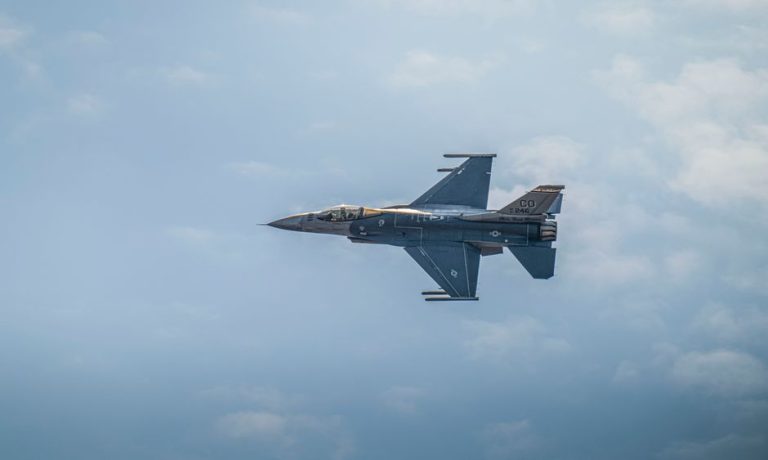 Military F-16 jet flying against a backdrop of clouds, showcasing aviation power.