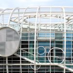 Top of contemporary glass building with creative white lattice and glass walls reflecting daylight
