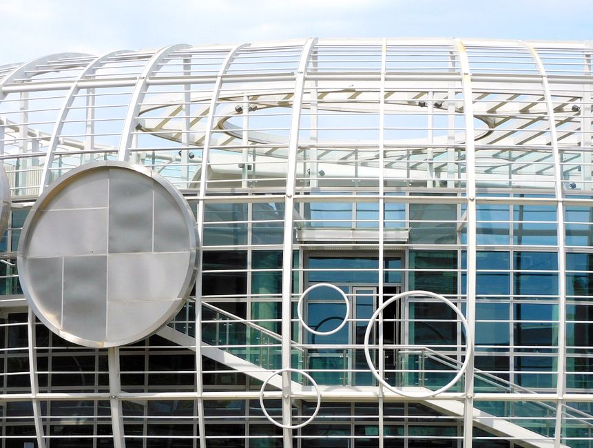 Top of contemporary glass building with creative white lattice and glass walls reflecting daylight