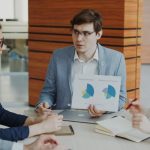 Organizational Efficiency: Communication Protocols and Strategy A team engaged in a business meeting discussing charts and strategies in an office.