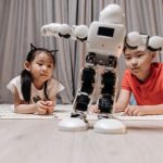 Children enjoying playtime with a modern android robot on a rug indoors.