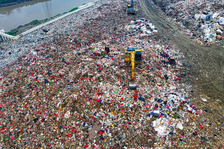 Birds-eye view of a bustling landfill in Banten with excavators working amidst the piles of waste.