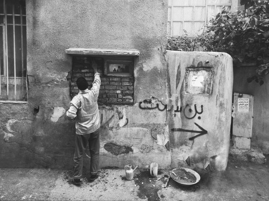 A candid urban street scene in Tehran, capturing daily life in monochrome.