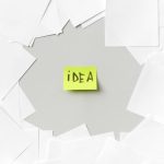 Yellow sticky note labeled 'Idea' surrounded by white papers, symbolizing creativity.