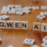 Scrabble-like tiles arranged to spell 'Qwen AI' on a wooden surface, depicting technology concepts.
