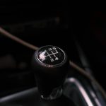 Detailed view of a car's manual transmission shift knob with visible gear pattern.
