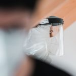 Close-up of a healthcare worker in a protective suit and face shield, emphasizing safety during the pandemic.