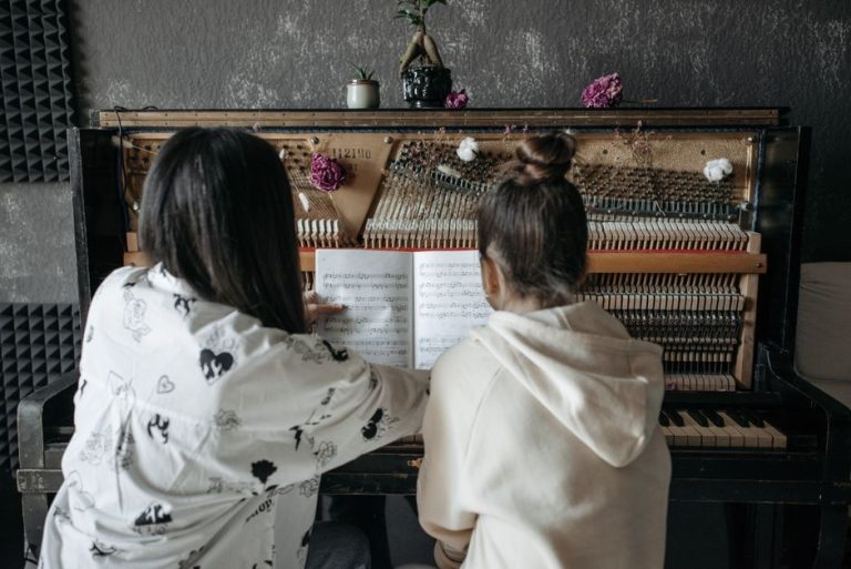 Back view of a piano lesson featuring a teacher guiding a student on music notation.
