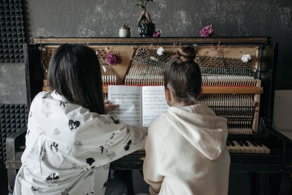 Back view of a piano lesson featuring a teacher guiding a student on music notation.