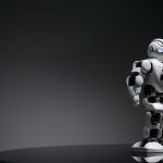 Programmable Matter: The Future of Adaptive Infrastructure Compact humanoid robot toy standing on a reflective surface, exuding a futuristic vibe.