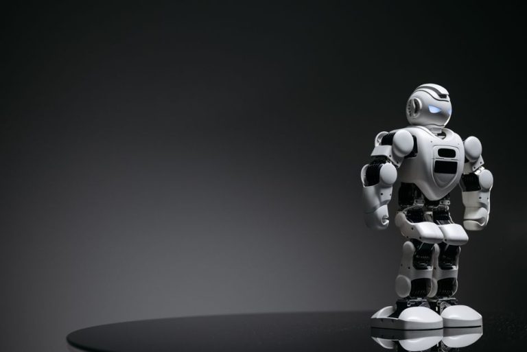 Compact humanoid robot toy standing on a reflective surface, exuding a futuristic vibe.