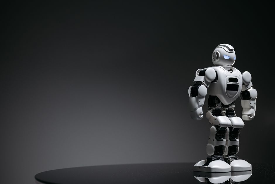 Compact humanoid robot toy standing on a reflective surface, exuding a futuristic vibe.