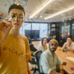 Radical Transparency: A Strategic Framework for High Performance Team engaging in a collaborative meeting, brainstorming on a glass board in a modern office.