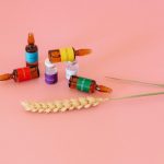 Studio shot of vaccine ampoules on a pink surface with wheat ears.