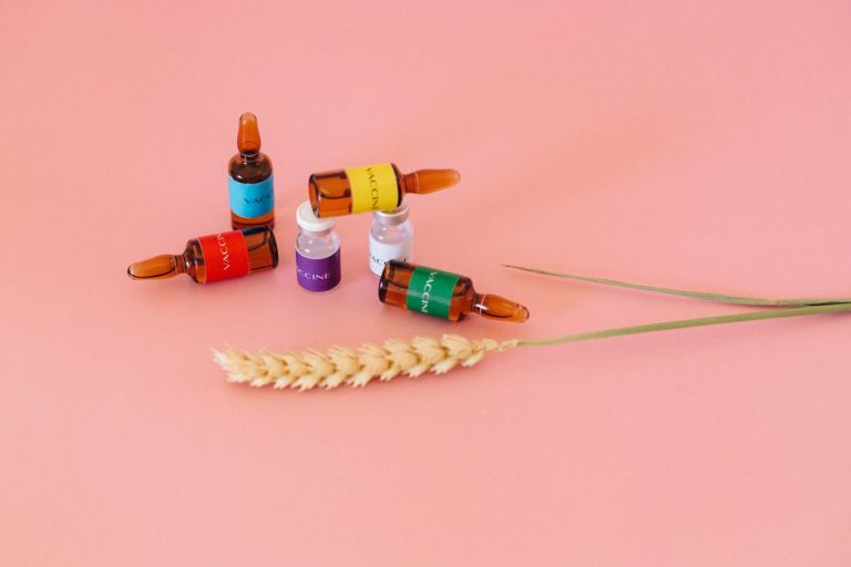 Studio shot of vaccine ampoules on a pink surface with wheat ears.
