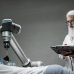 Remote Robotic Surgery & The Future of Operational Excellence Senior scientist observing robot performing a task indoors.