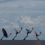 Satellite Internet Strategy: Scaling Business Operations Globally Four satellite dishes on a rooftop against a cloudy sky in Cancún, Mexico.