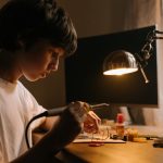 Self-Repairing Electronics: The Future of Hardware Resilience Young teen focused on soldering circuit board at desk. Engaging in hands-on technical skills.