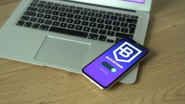 Smartphone displaying blockchain application resting on a laptop, symbolizing modern technology and finance.