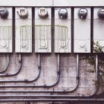 Smart Grid Optimization: A Strategic Asset for Enterprise Array of outdoor electric meters on a brick wall with vines.