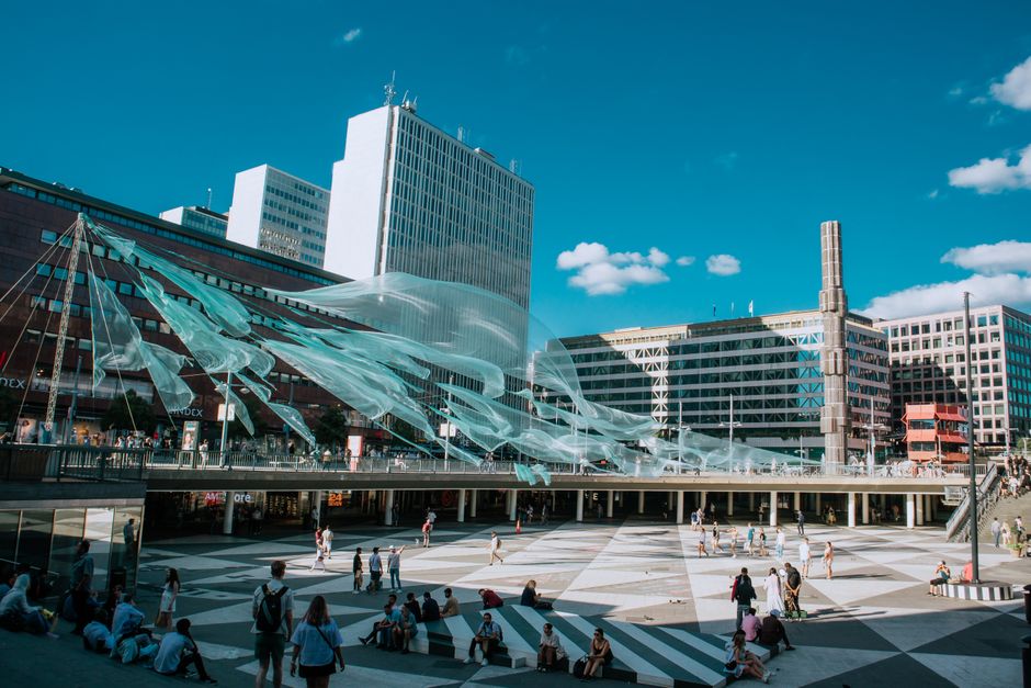 Vibrant urban square with modern art installations and people enjoying a sunny day.