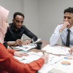 A diverse team of professionals engaged in a focused business meeting discussing documents and data.