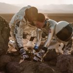 Two astronauts planting a seedling in a rocky desert terrain, symbolizing space colonization.