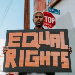 A person holding an 'Equal Rights' sign during a peaceful protest on the street.