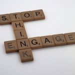 Wooden Scrabble tiles spelling 'Stop Think Engage' for strategic concepts.