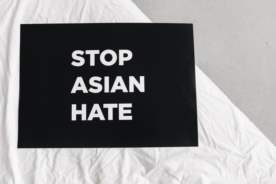Black sign with 'Stop Asian Hate' on white fabric, promoting social justice.