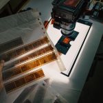 Close-up of film negatives being digitized using a camera and lightbox.