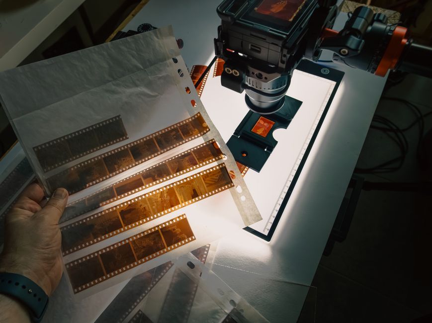 Close-up of film negatives being digitized using a camera and lightbox.