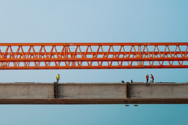 Workers and red crane on a bridge construction in Chilmari, Bangladesh.