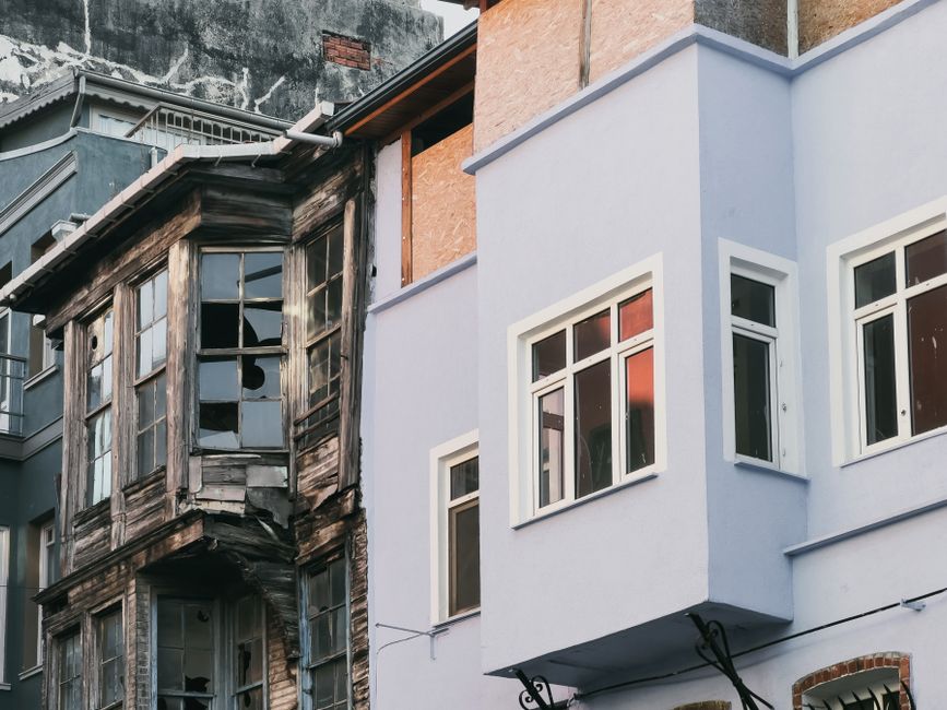 A stark contrast between decaying and modern urban building exteriors.
