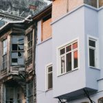 Structural Fragility: Lessons in Governance & Strategy | 2026 A stark contrast between decaying and modern urban building exteriors.