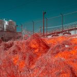 Infrared photo of an industrial plant with surreal hues, depicting environmental impact.