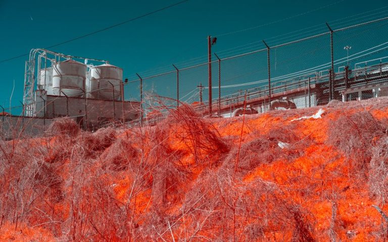 Infrared photo of an industrial plant with surreal hues, depicting environmental impact.