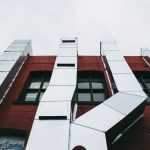 Low angle view of a modern industrial facade with prominent metal ducts on a red brick building.