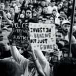 Technocratic Governance: Why Human Judgment Beats Algorithms Crowd of young adults protesting with impactful signs in black and white.
